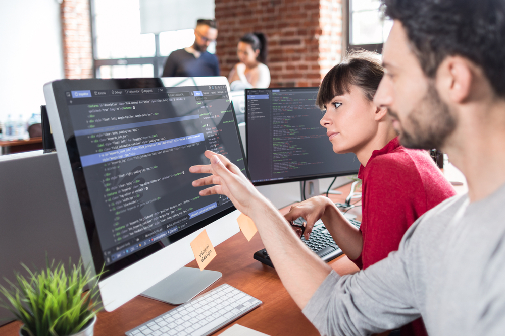 coworkers looking at computer code