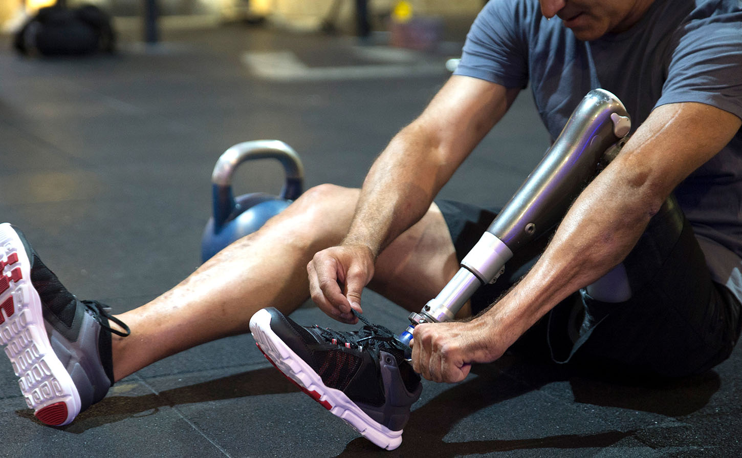 man with prosthetic leg tying his shoes