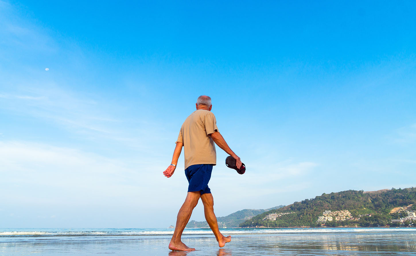 retired man walking on the beach