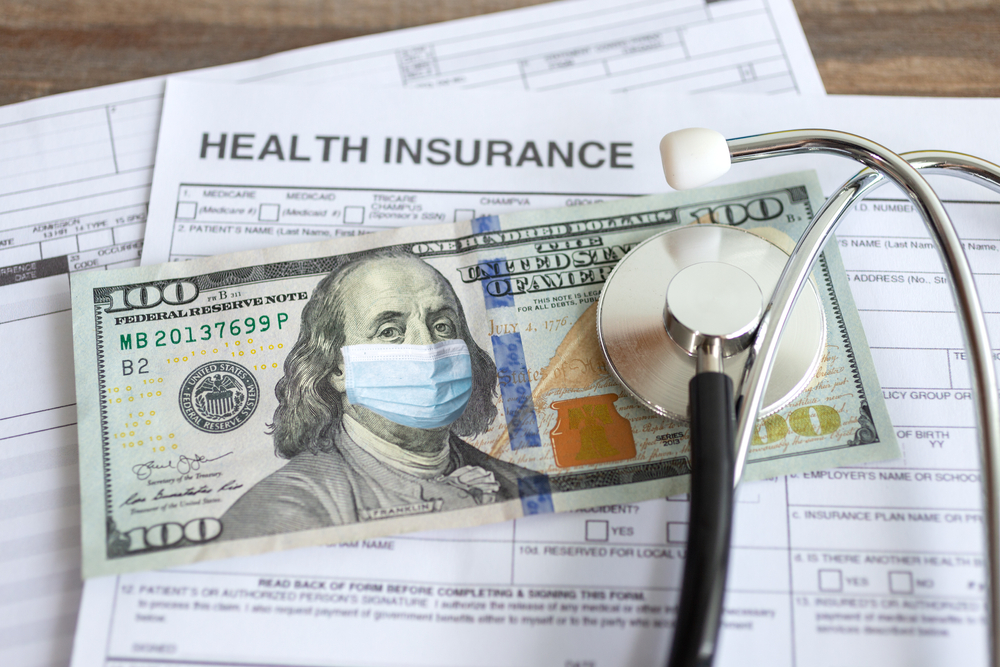 health insurance paperwork with a $100 and stethoscope