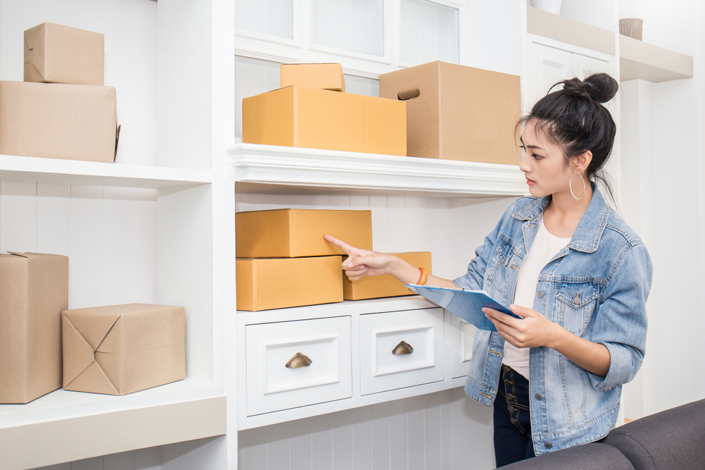 woman looking at boxes and an inventory list